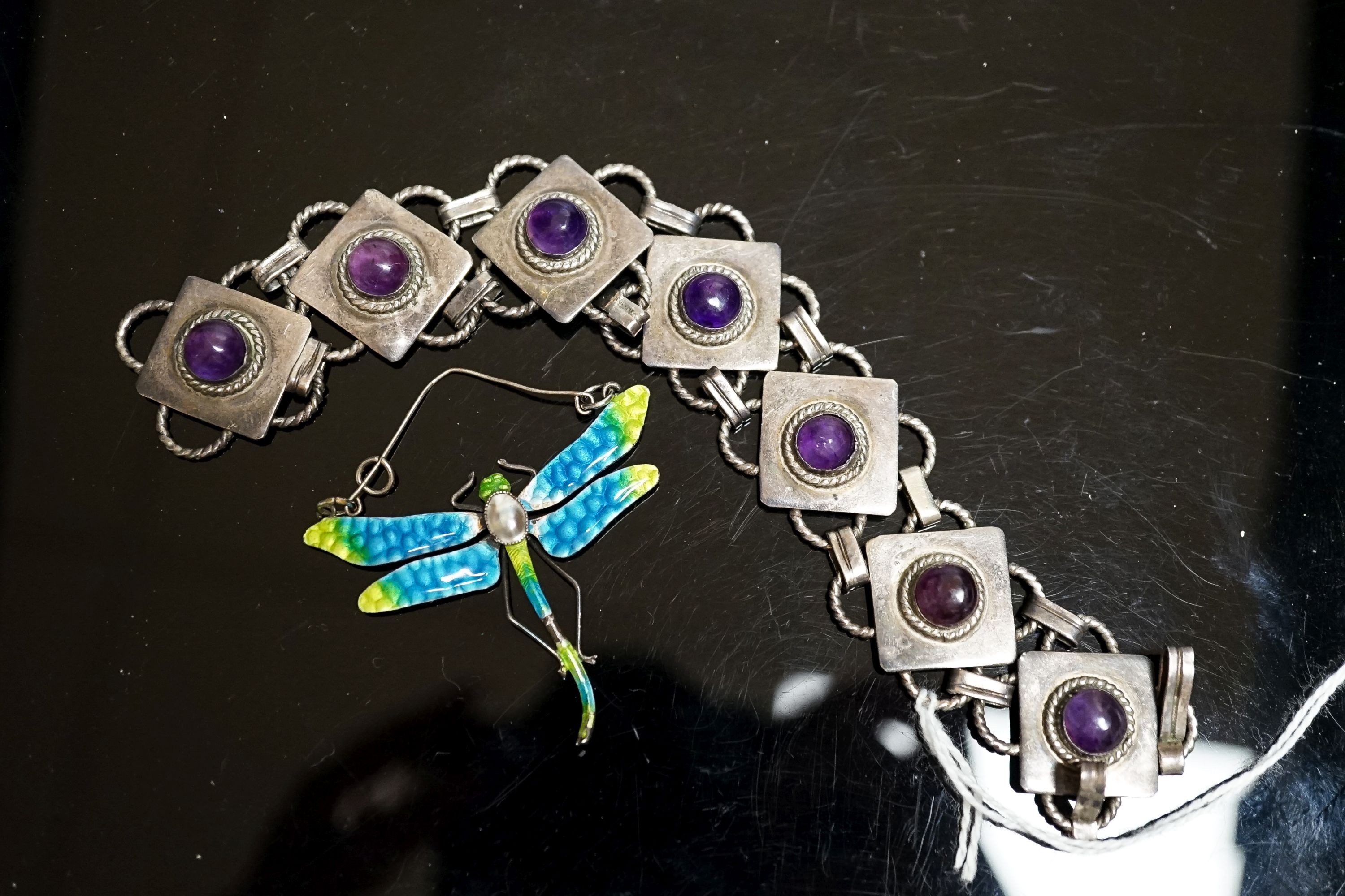 A white metal and seven stone cabochon amethyst set bracelet, 18.5cm and a white metal, mother of pear, and enamel set dragonfly pendant(a.f.), diameter 47mm.